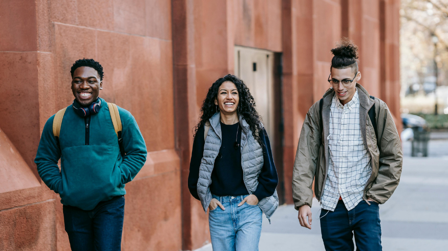A happy diverse group of mates walking along street.